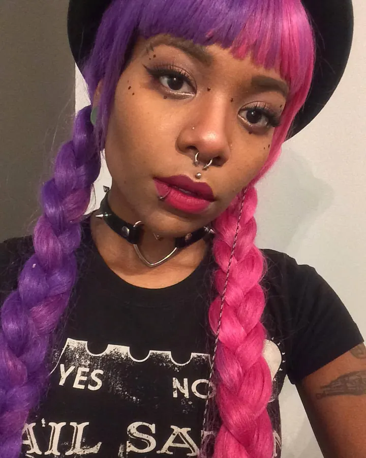 Femme trans aux cheveux châtains, en sous-vêtements noirs, posant sur un lit