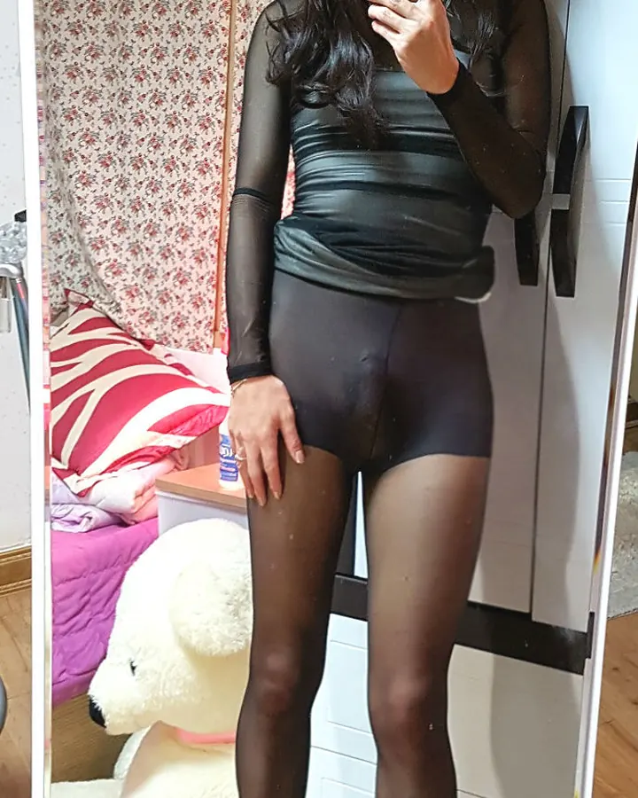 Nina en body noir et collants, miroir, perruque foncée et talons