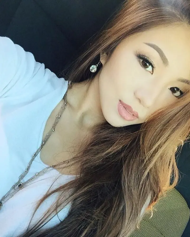 Jeune femme trans latino aux cheveux blonds, prenant un selfie dans une voiture, regardant l'objectif avec un sourire discret